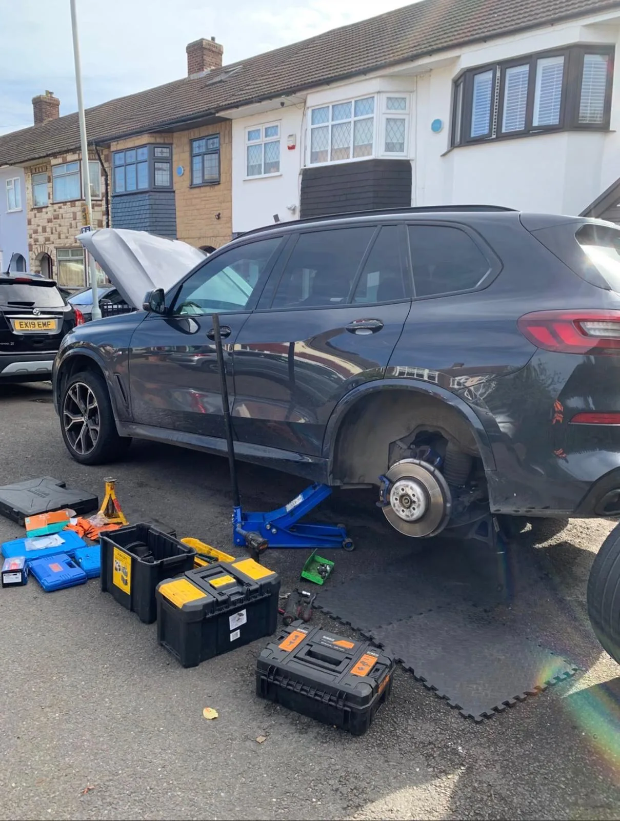 Mobile brake repair on a BMW X5 at the customer's home, wheel removed and brake disc exposed